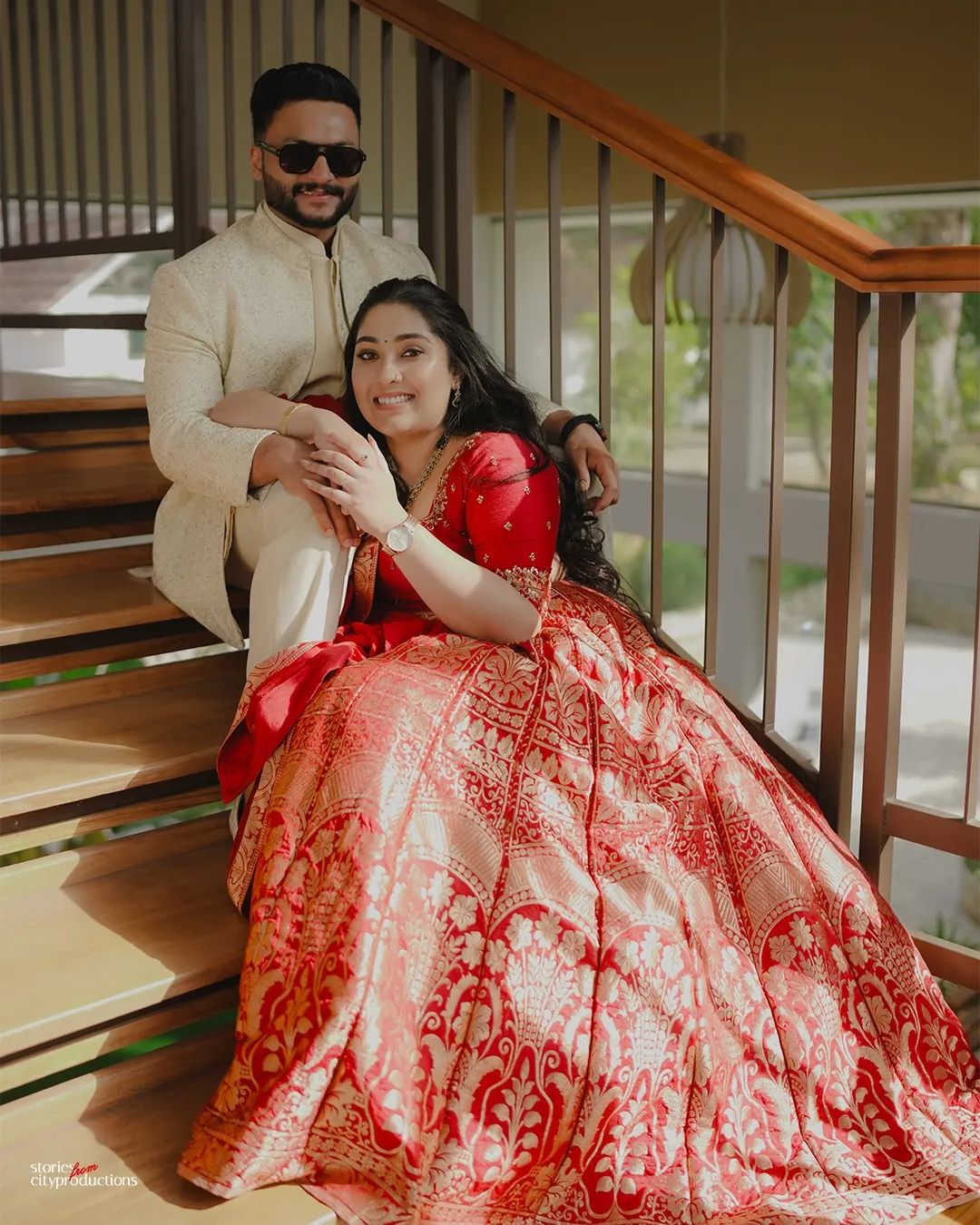 Engaged couple posing together beside a staircase